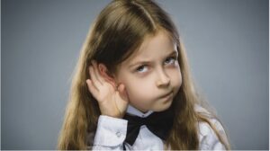 girl with her hand wrapped around her ear listening
